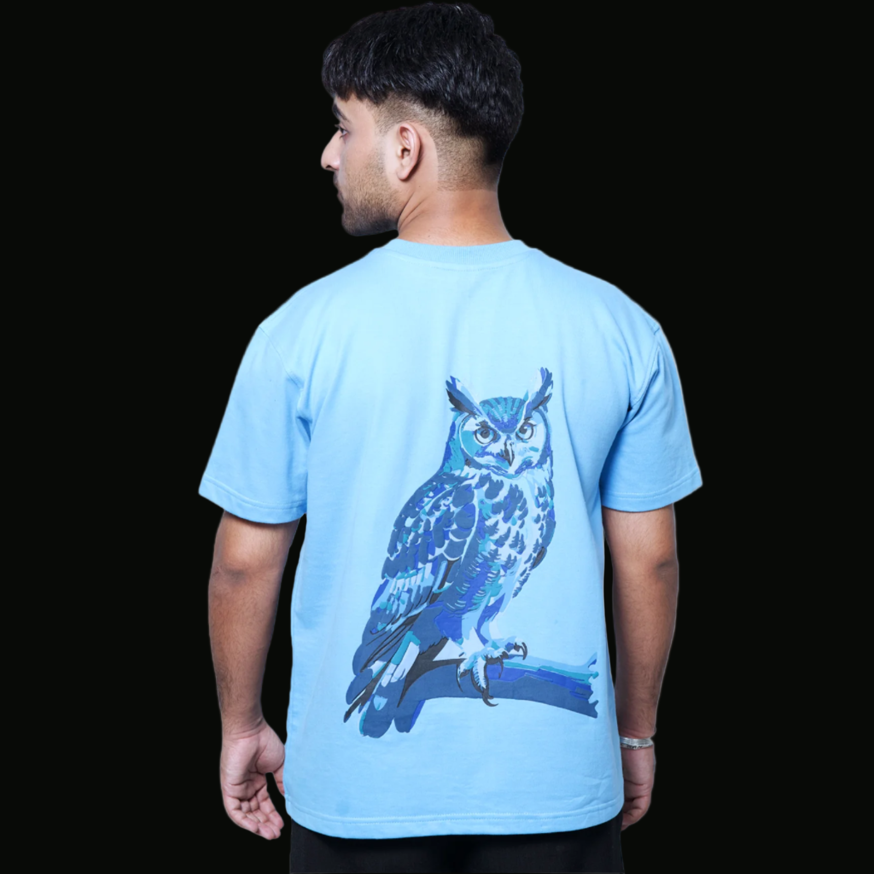 A person wearing a blue t-shirt with a graphic of an owl on the back.